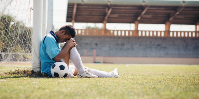 Sad Young Soccer player with ball on field