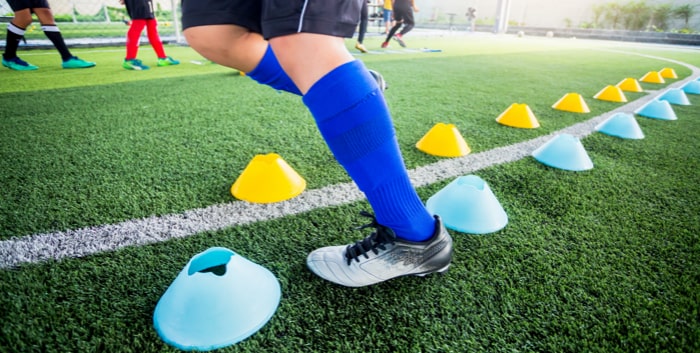 Soccer player Jogging and jump between cone markers for soccer training