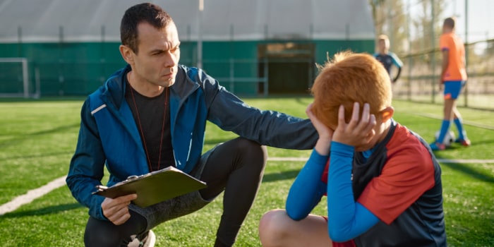 Coach comforting a young soccer player after missed goal